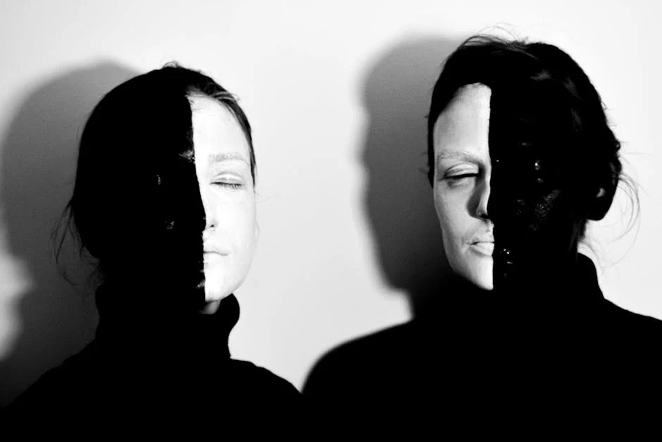 Black and white of models with face covered with black and white paints standing with closed eyes against white background